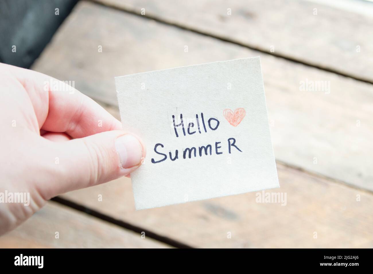Hallo Sommer. Kreatives Konzept. Hand mit einem Anhänger mit der Aufschrift. Stockfoto