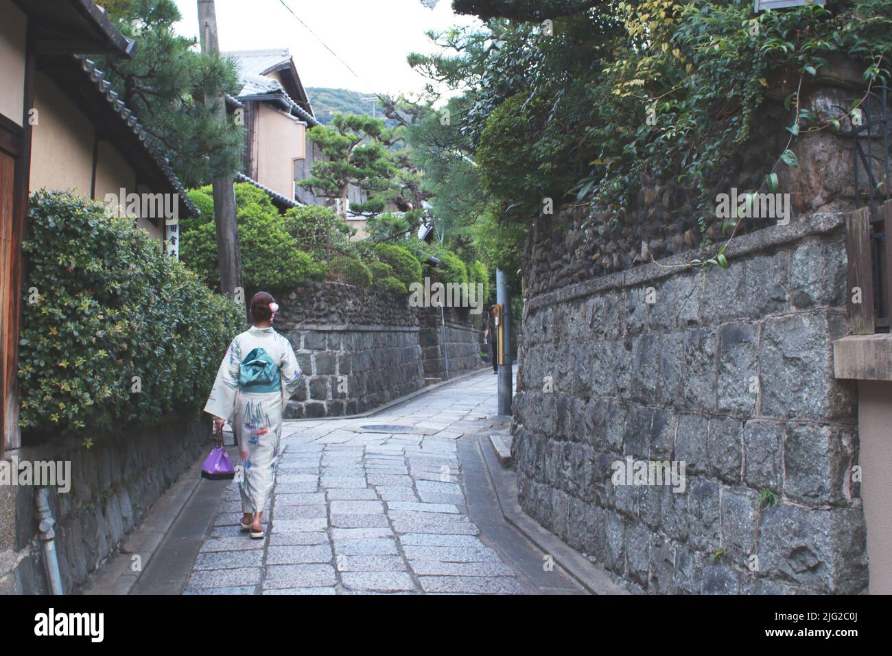 Eine Japanerin, die eine Yukata trägt und in Kyoto, Japan, eine enge Straße entlang läuft. Stockfoto