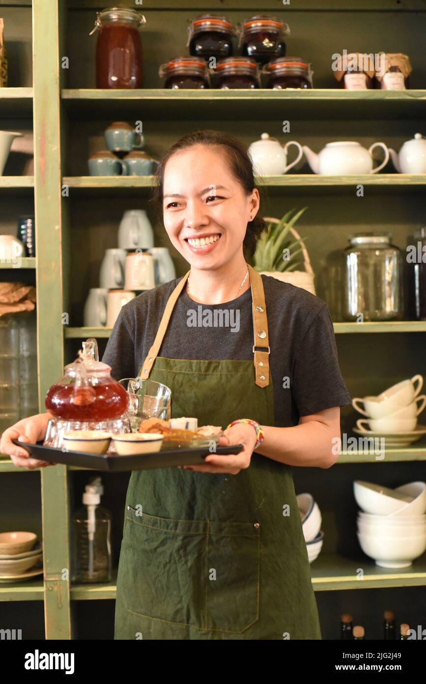Vietnamesische junge Frau, die in einem Café Tee serviert Stockfoto