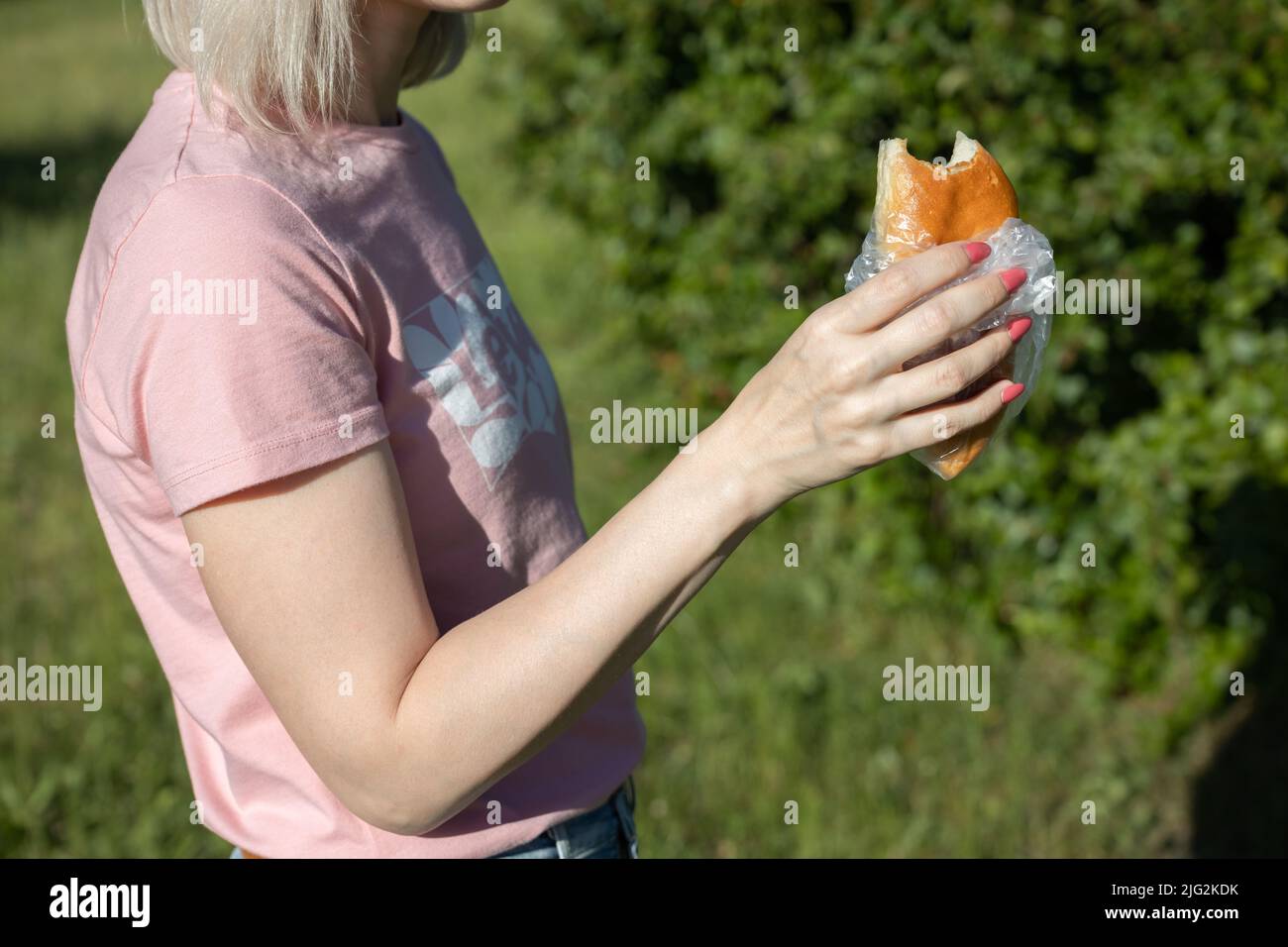 Mädchen hält einen gebissenen Kuchen in der Hand Stockfoto