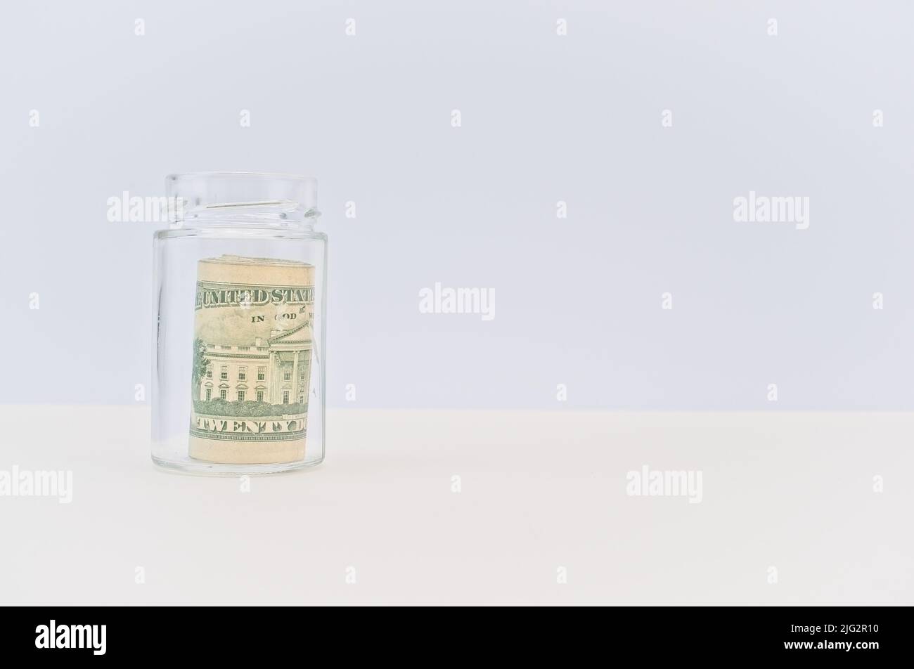 US-Banknoten Rollen in einem Glas mit weißem Hintergrund Stockfoto