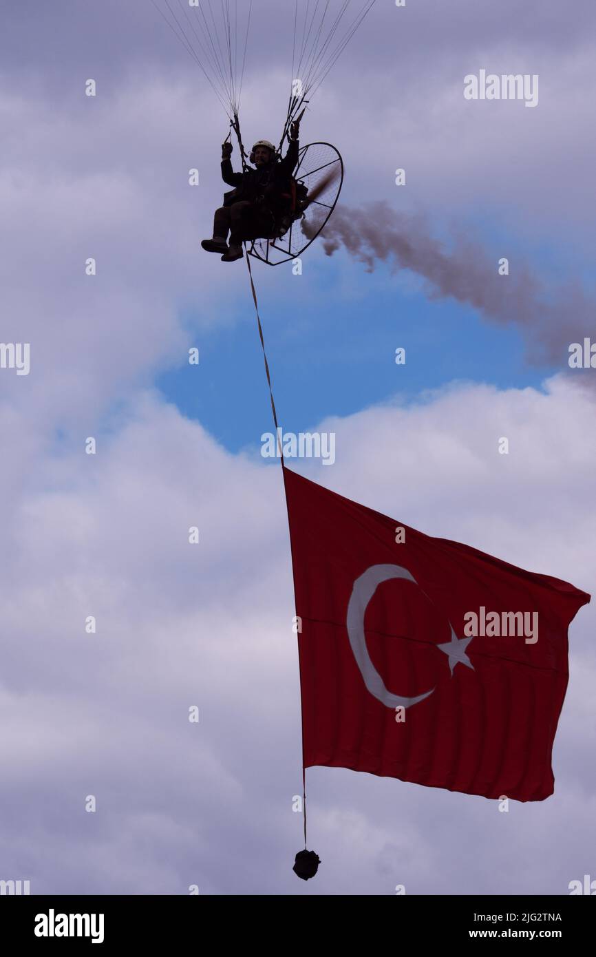 Türkischer Fallschirmspringer fliegt und schleppt türkische Flagge für eine Flugshow an einem bewölkten Tag Stockfoto