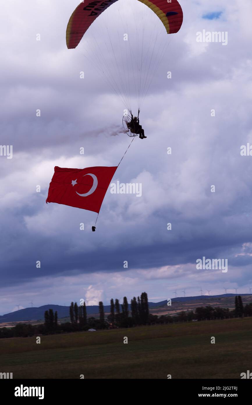Türkischer Fallschirmspringer fliegt und schleppt türkische Flagge für eine Flugshow an einem bewölkten Tag Stockfoto