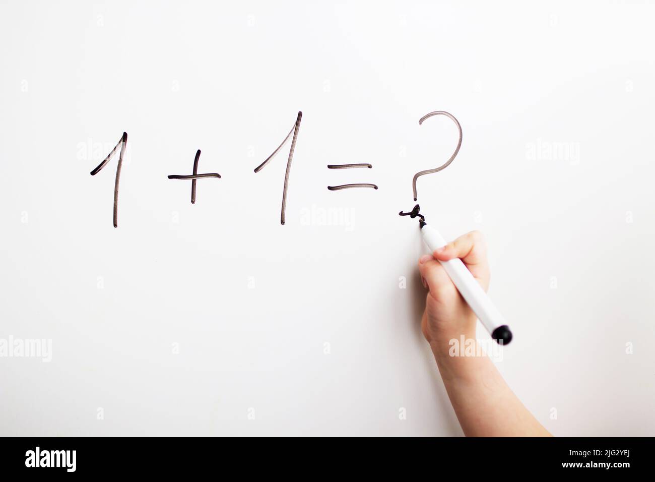 Eins plus eins. Kind löst ein Beispiel Stockfoto