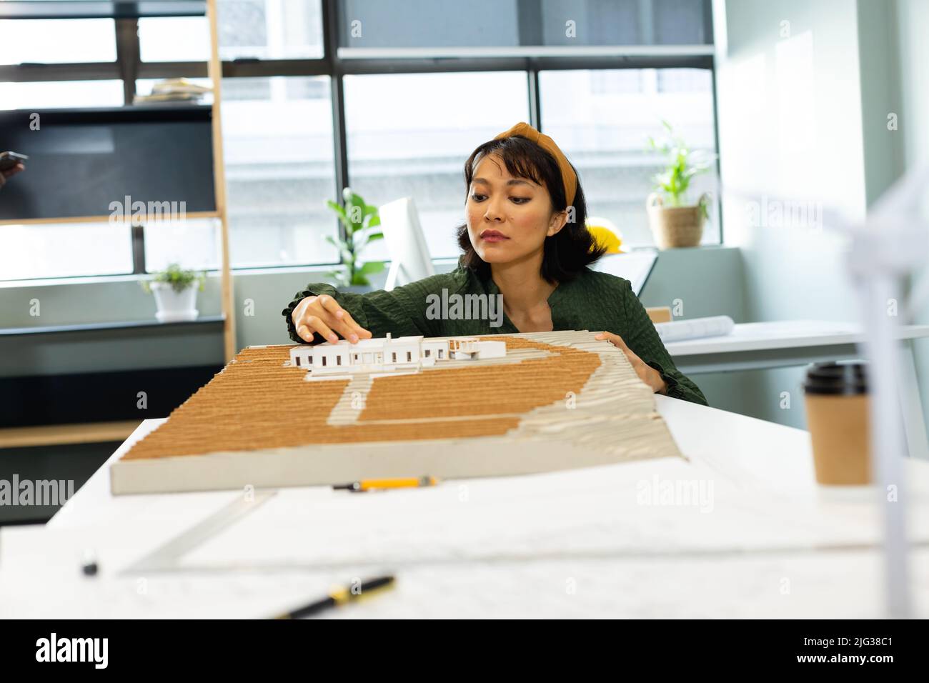 Asiatische junge Architektin analysiert Architekturmodell im Büro Stockfoto