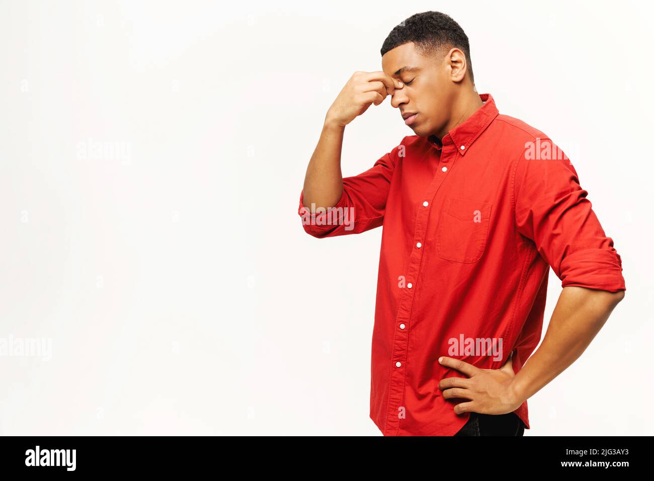 Problem, Depression oder Krankheit. Porträt eines traurigen, allein hübschen jungen Mannes im Hemd stehend, den Kopf nach unten haltend und weinend. Innenaufnahme des Studios isoliert auf weißem Hintergrund Stockfoto