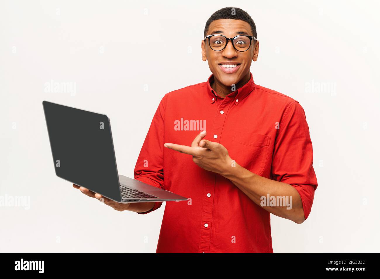 Porträt eines schockierten, überraschten Mannes, der seinen Laptop hält und mit großen, erstaunten Augen auf die Kamera blickt. Innenaufnahme des Studios isoliert auf weißem Hintergrund Stockfoto