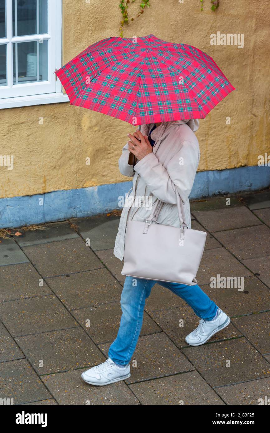 Besucher, die bei strömendem Regen in Oxford, Oxfordshire, Großbritannien, an einem regnerischen Tag im August mit einem Tartanschirm spazieren gehen Stockfoto