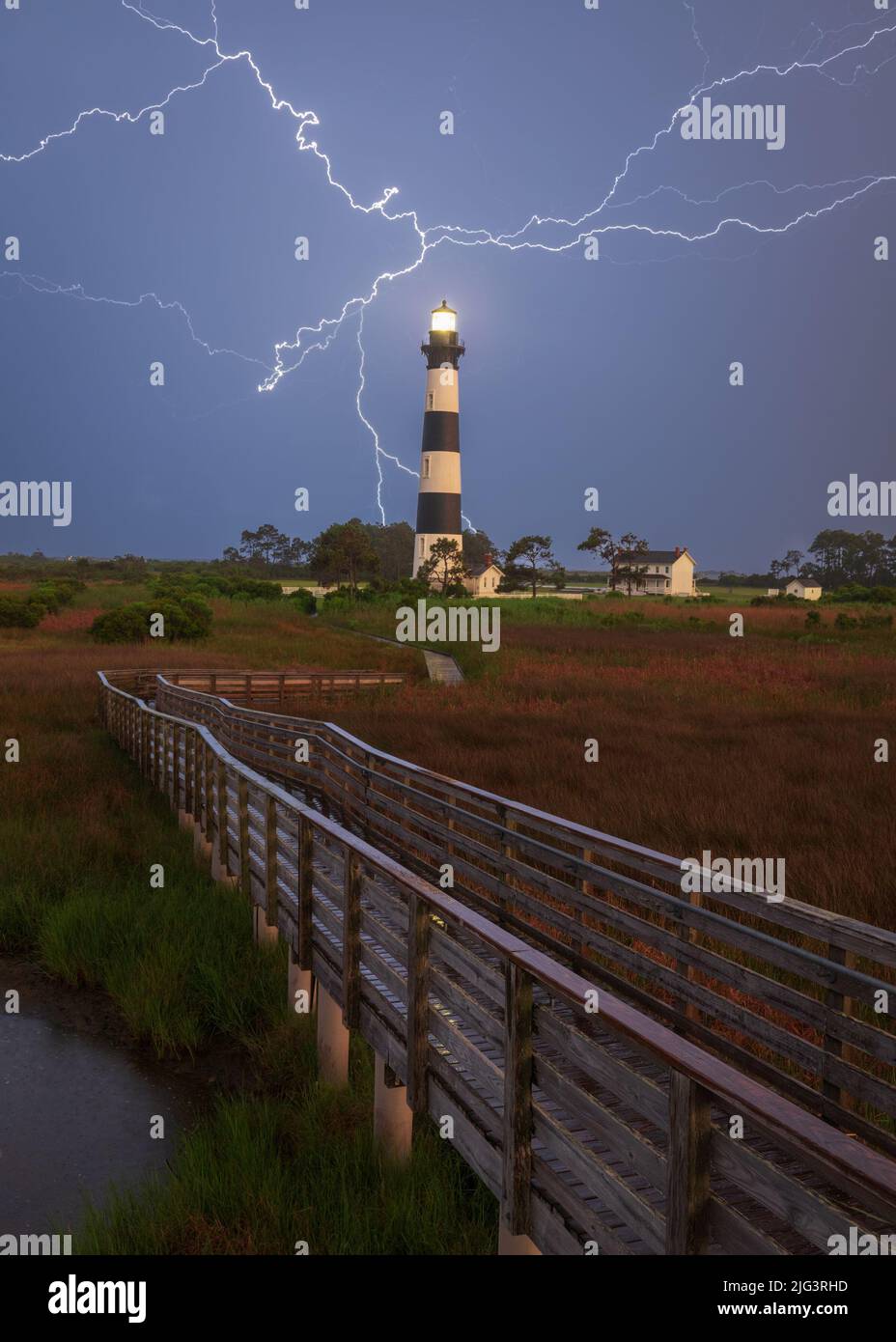 Promenade zum Bodie Island Lighthouse mit Blitzeinschlag im Hintergrund bei Regen in der Nacht, Outer Banks, North Carolina Stockfoto