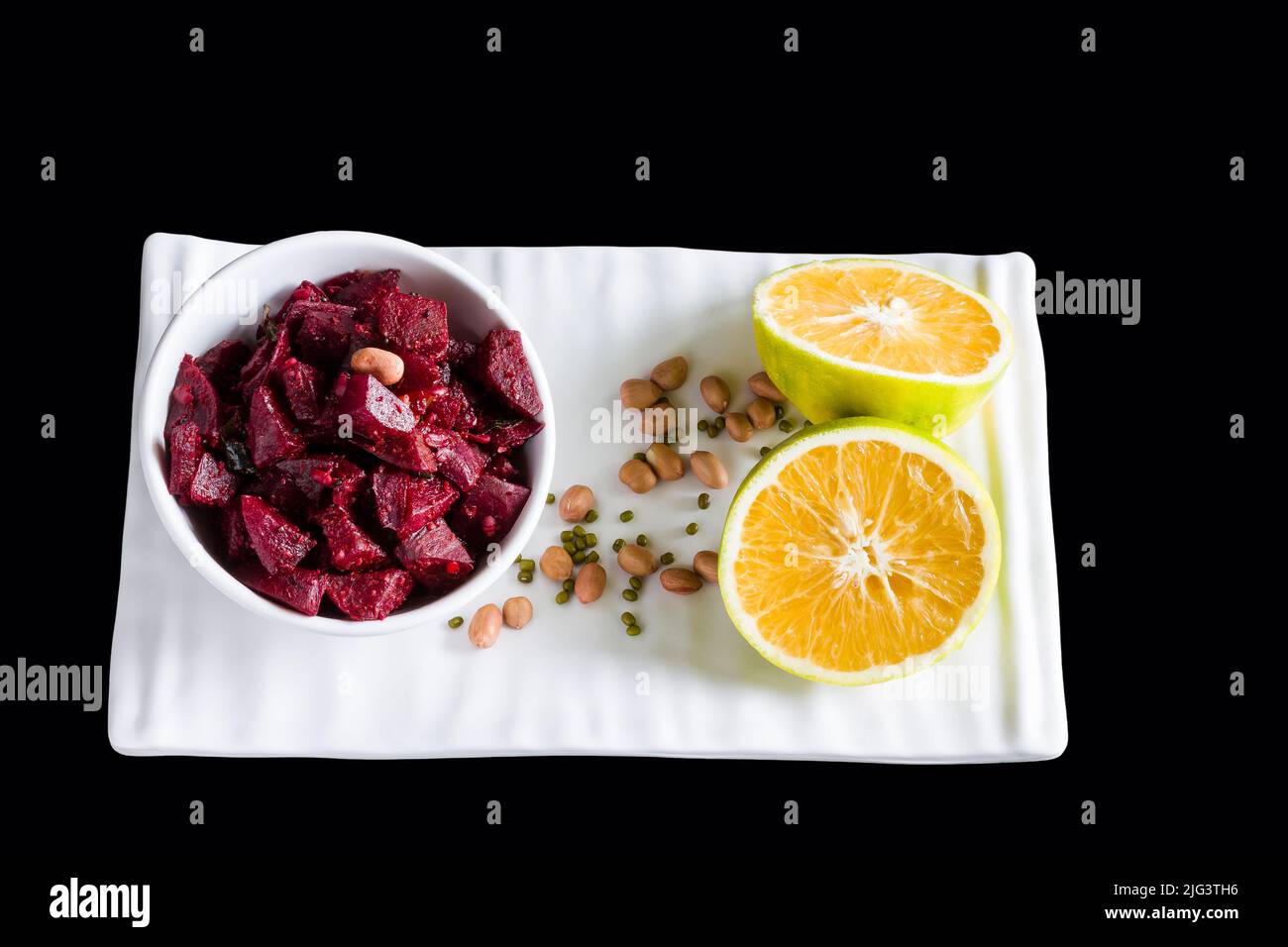 Gebratenes oder sautiertes Rote-Beete-Gemüse, garniert mit Erdnüssen, Minze, süßem Limettensaft, halbgeschnittener süßer Limettenfrucht. Indisches Gericht auf schwarzem Hintergrund. Stockfoto