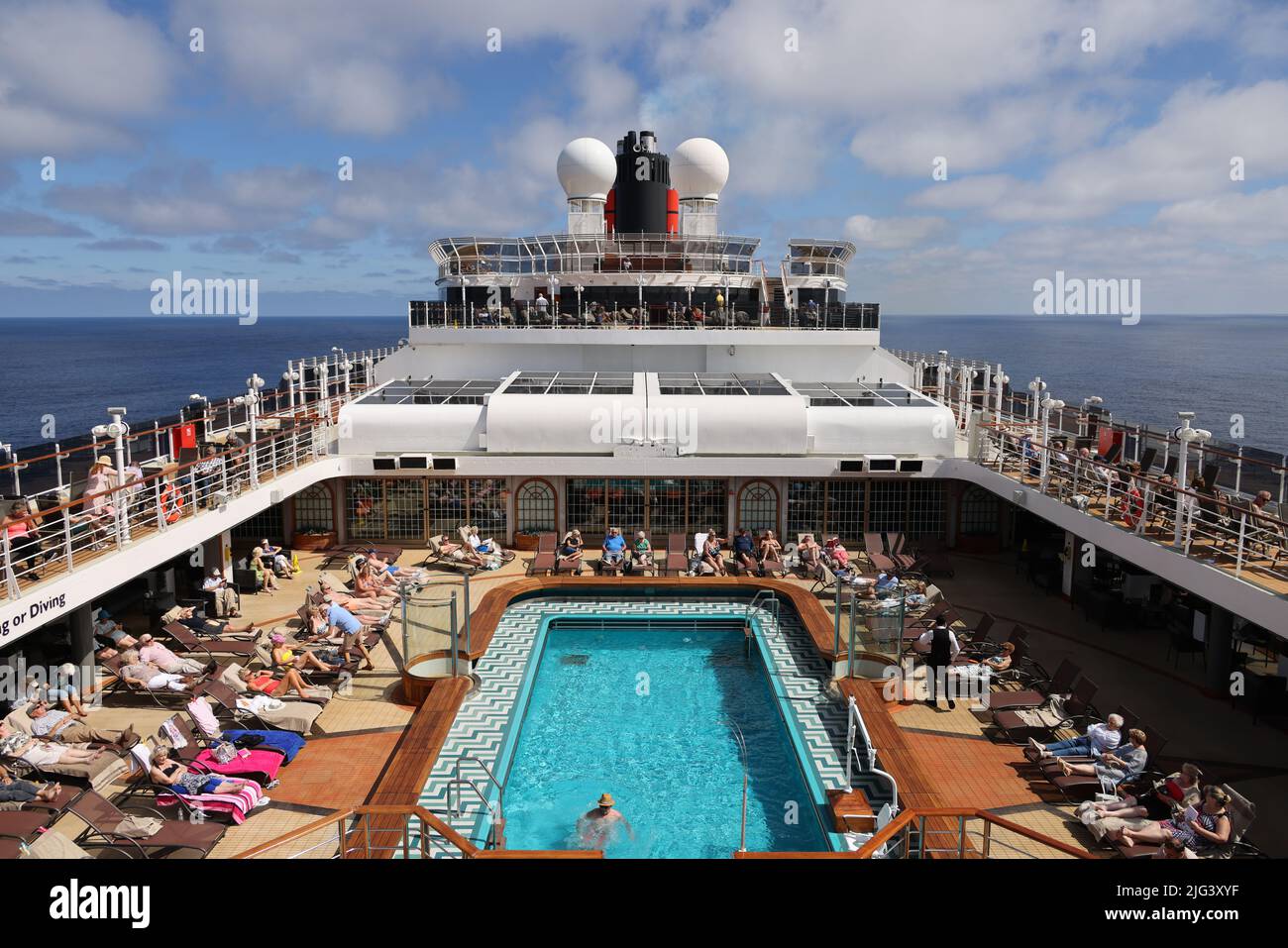 Massen von reifen Passagieren entspannen sich auf einem sonnigen Kreuzfahrtdeck, während die Industrie nach der Coronavirus-Pandemie langsam wieder in den normalen Betrieb zurückkehrt. Stockfoto