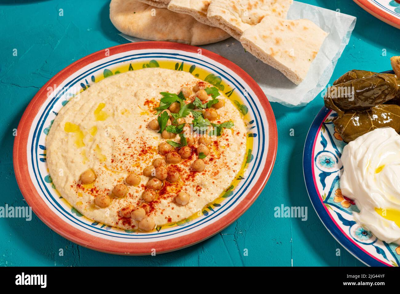 Traditionelle orientalische, mediterrane arabische Mahlzeit aus Fladenbrot, Hummus, Dolma und Joghurt, garniert mit Kräutern, Paprika und Olivenöl Stockfoto