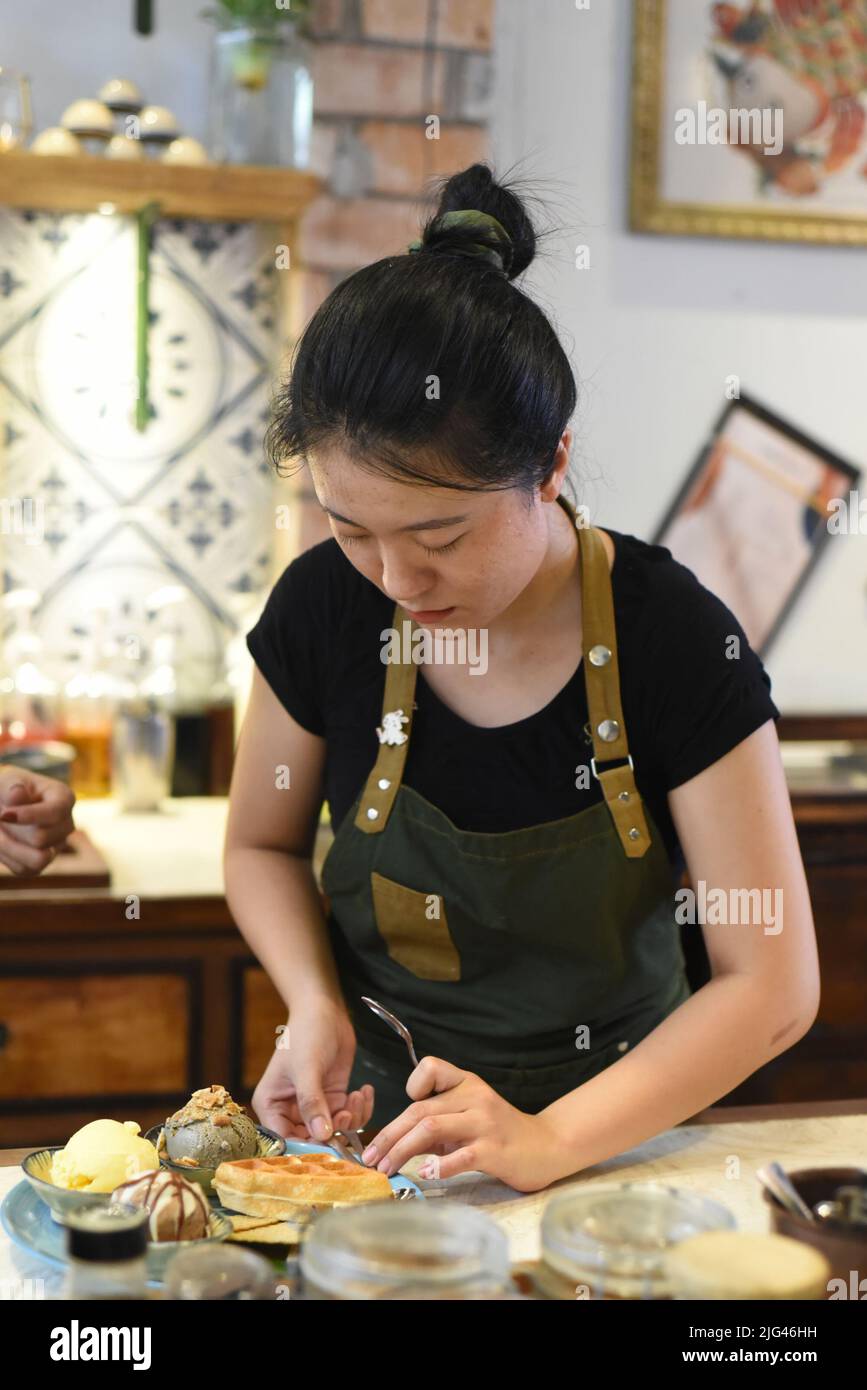 Vietnamesische junge Kellnerin bereitet hausgemachtes Eis für einen Kunden vor Stockfoto