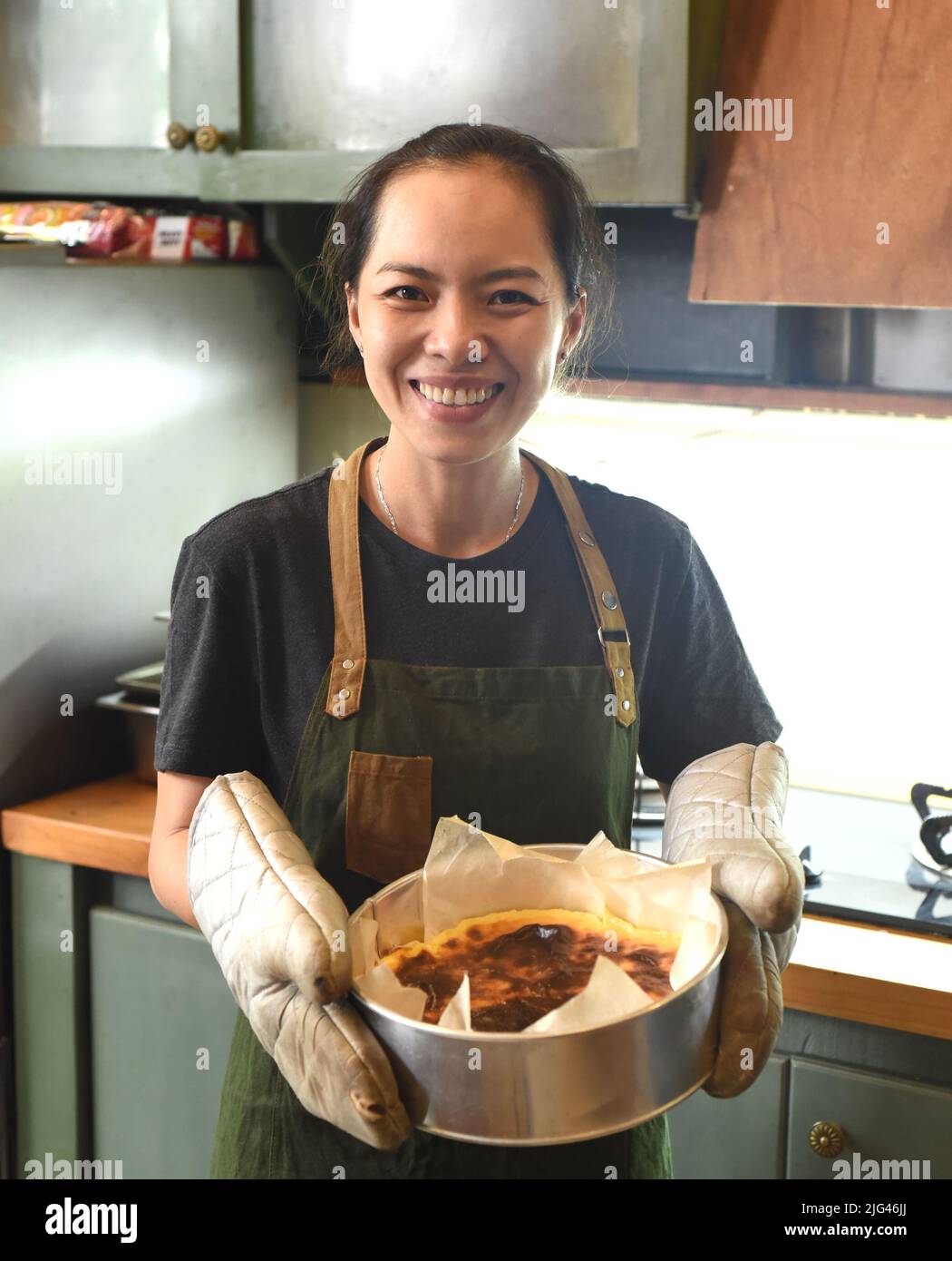 Eine Vietnamesin hält frisch gebackenen Kuchen im Ofenhandschuh Stockfoto