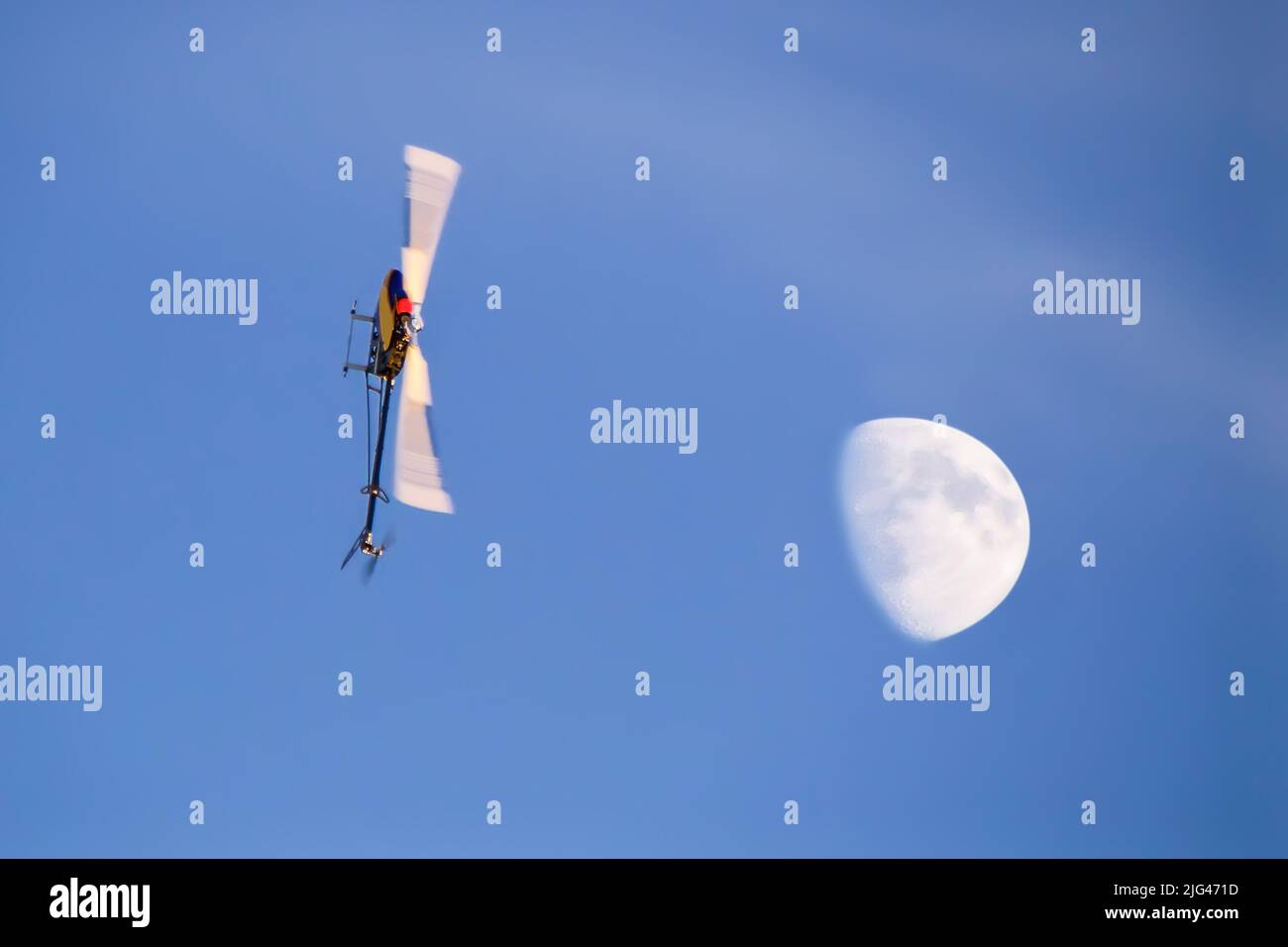 Funkgesteuerter Modellhubschrauber, der bei Sonnenuntergang Luftakrobatik macht Stockfoto