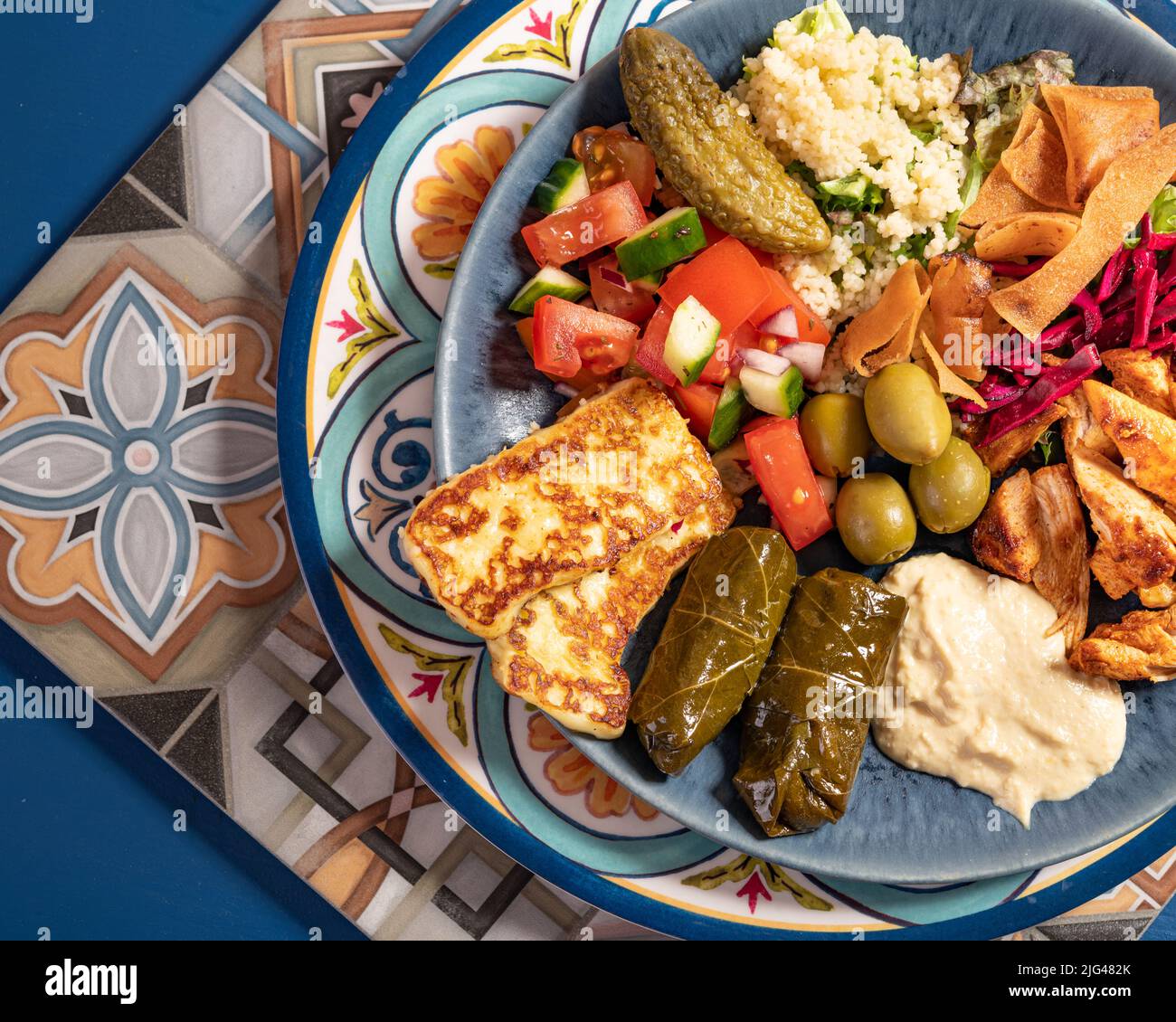 Eine Portion traditioneller östlicher mediterraner arabischer Speisen wie Hummus, Oliven, gegrilltes Huhn, Halloumi, Dolma, Couscous, Salat und pickl Stockfoto