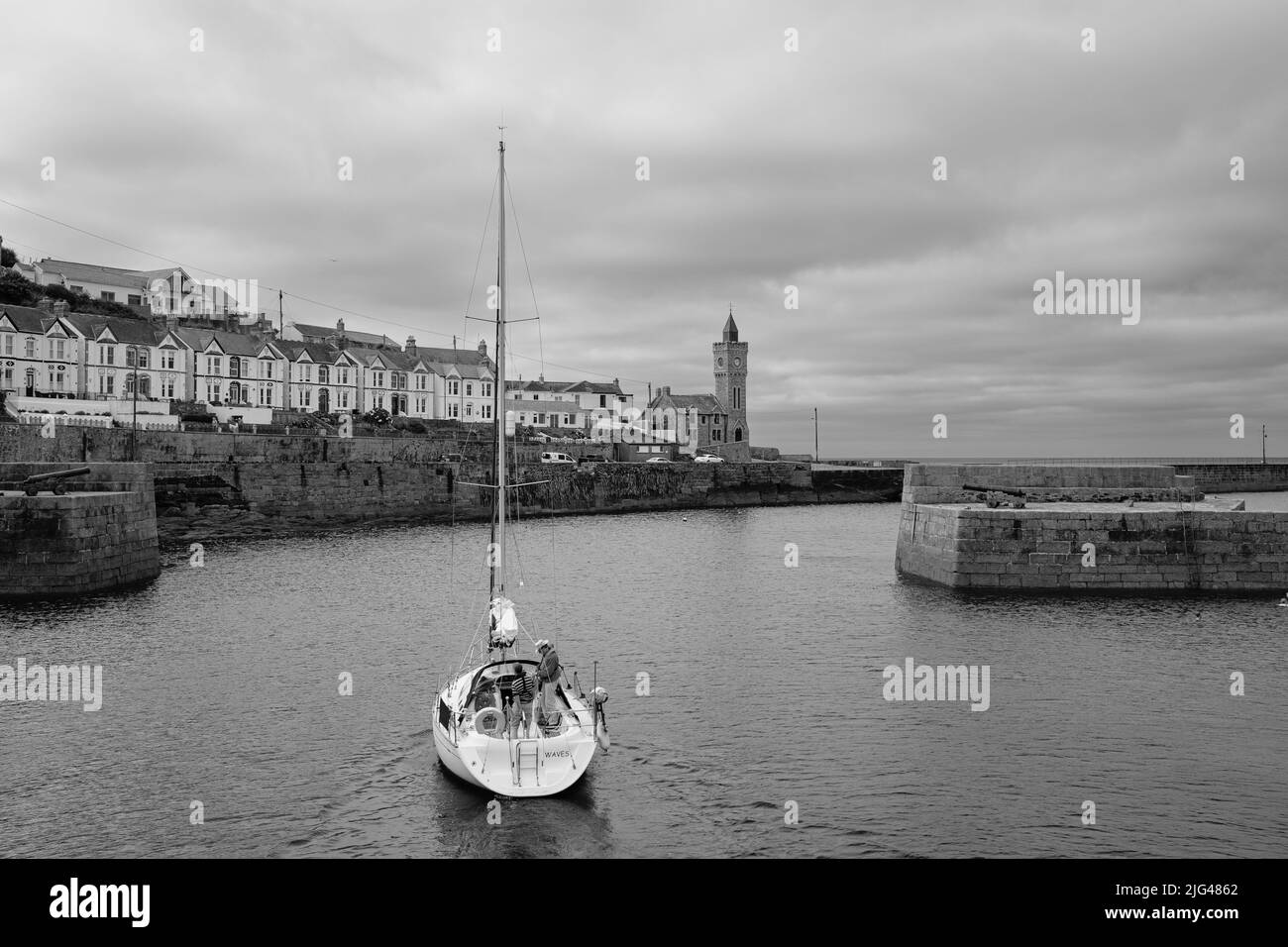 Eine Yacht, die den Hafen von Porthleven, Cornwall verlässt Stockfoto