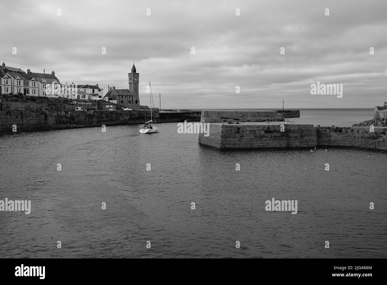 Eine Yacht, die den Hafen von Porthleven, Cornwall verlässt Stockfoto