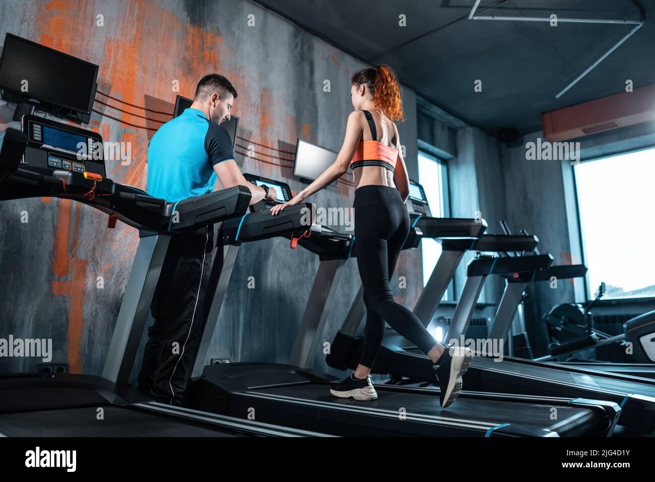 Junge schöne Frau hat Training auf dem Laufband mit Personal Trainer und Laufen Stockfoto