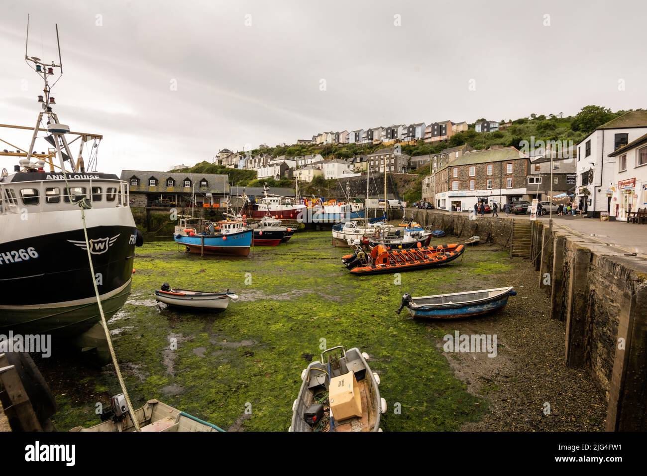 Schiffe und Boote sind bei Ebbe hoch und trocken im Fischereihafen von Mevagissey, Cornwall, Großbritannien Stockfoto