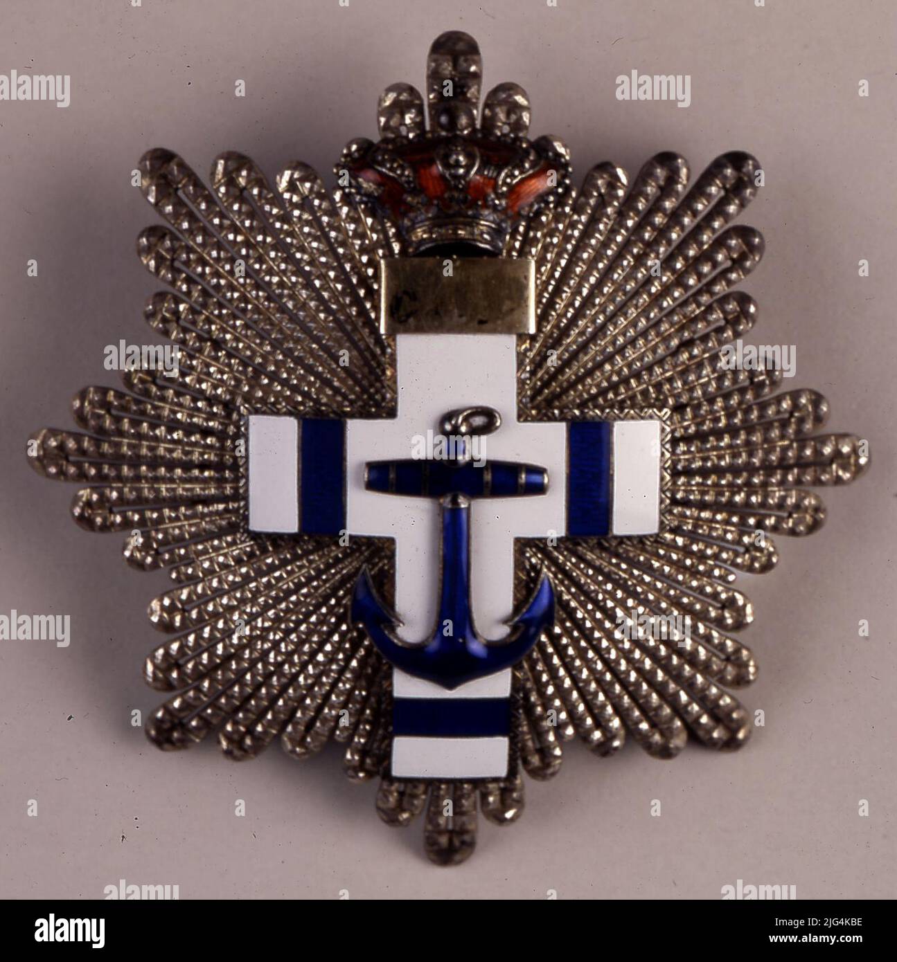 Cruz des Marineverdienstordens mit weißer Unterscheidungskraft, Pensionsklasse 3.. Herrschaft von Alfonso XIII. Cruz Order of Naval Merit mit weißem Unterscheidungszeichen - Klasse 3.. Marineverdienstorden. Reign Alfonso XIII Dritte Klasse Kreuz - Weiß-Rentner Unterscheidungskraft. Dekoration auf einer achtspitzigen konkaven sternförmigen Platte. Bestehend aus einem Satz von 88 Goldstrahlen, die sich zu Bursts vereinen. Jede Gruppe von Strahlen besteht aus fünf doppelten und einer einfachen Strahlen, facettierte imitierende Perlen mit abgerundeten Spitzen. Ráfagas Paradas nach Strahlen Dehnungsstreifen. Ein lateinisches vierarms lateinisches Kreuz überlappt sich auf der goldenen Böe. Vorderseite: Die Stockfoto