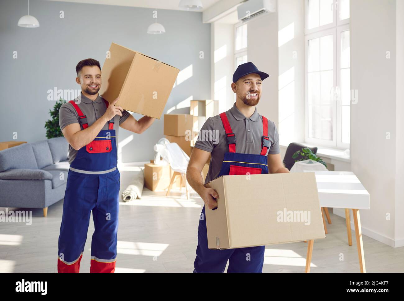 Die Lader des Umzugsunternehmens und des Lieferunternehmens nehmen Kartons aus dem Wohnzimmer. Stockfoto