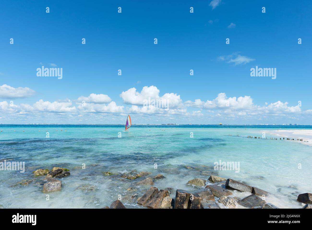 Unkenntlich Windsurfing Mann in der Nähe eines tropischen Strandes in Isla Mujeres, Mexiko. Im Hintergrund ist der blaue Himmel zu sehen. Konzept-Sporturlaub Stockfoto