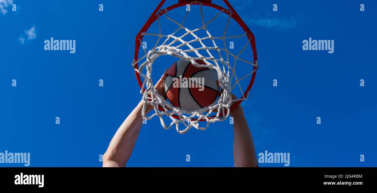 dunk im Korb. slam Dunk in Bewegung. Sommer-Aktivität. Lächelnder Mann mit Basketball-Ball. Horizontales Posterdesign. Web-Banner-Header, Kopierbereich. Stockfoto