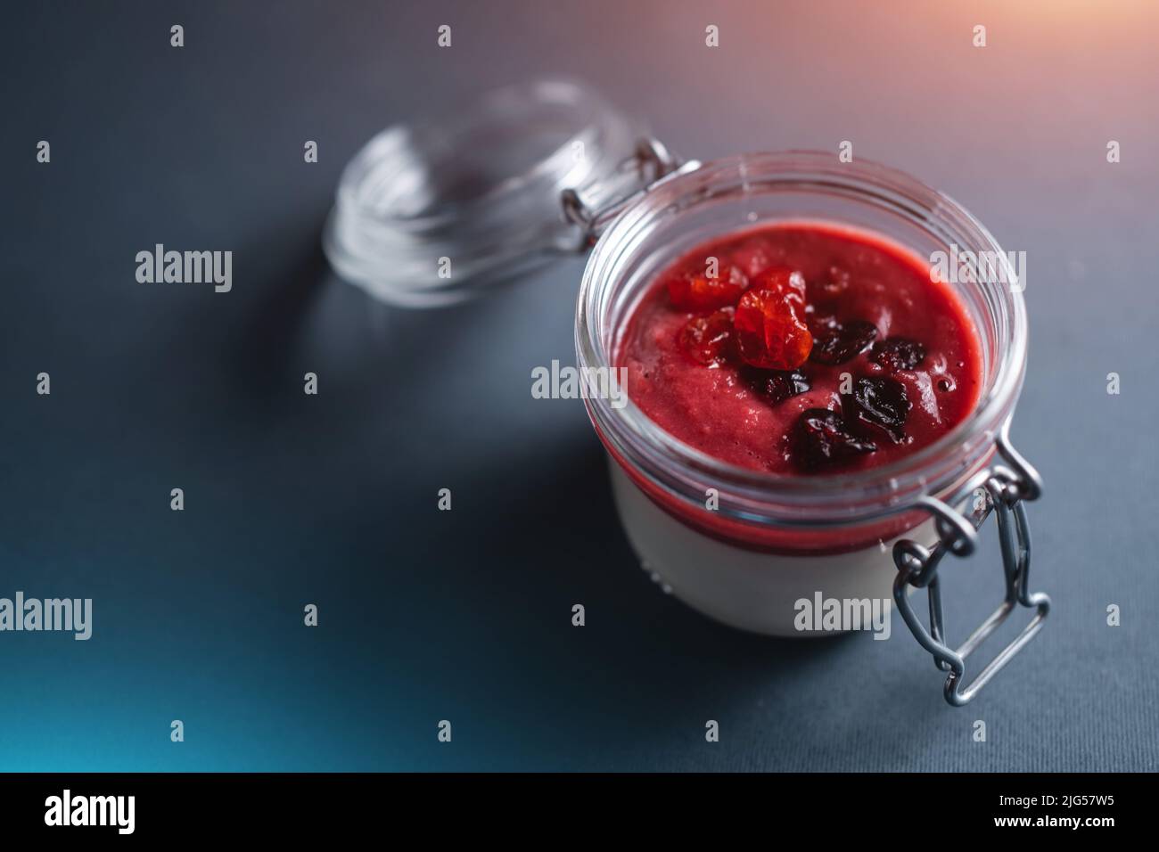 beere Panna Cotta Dessert mit Kirschsauce im Glas auf schwarzem Hintergrund Stockfoto