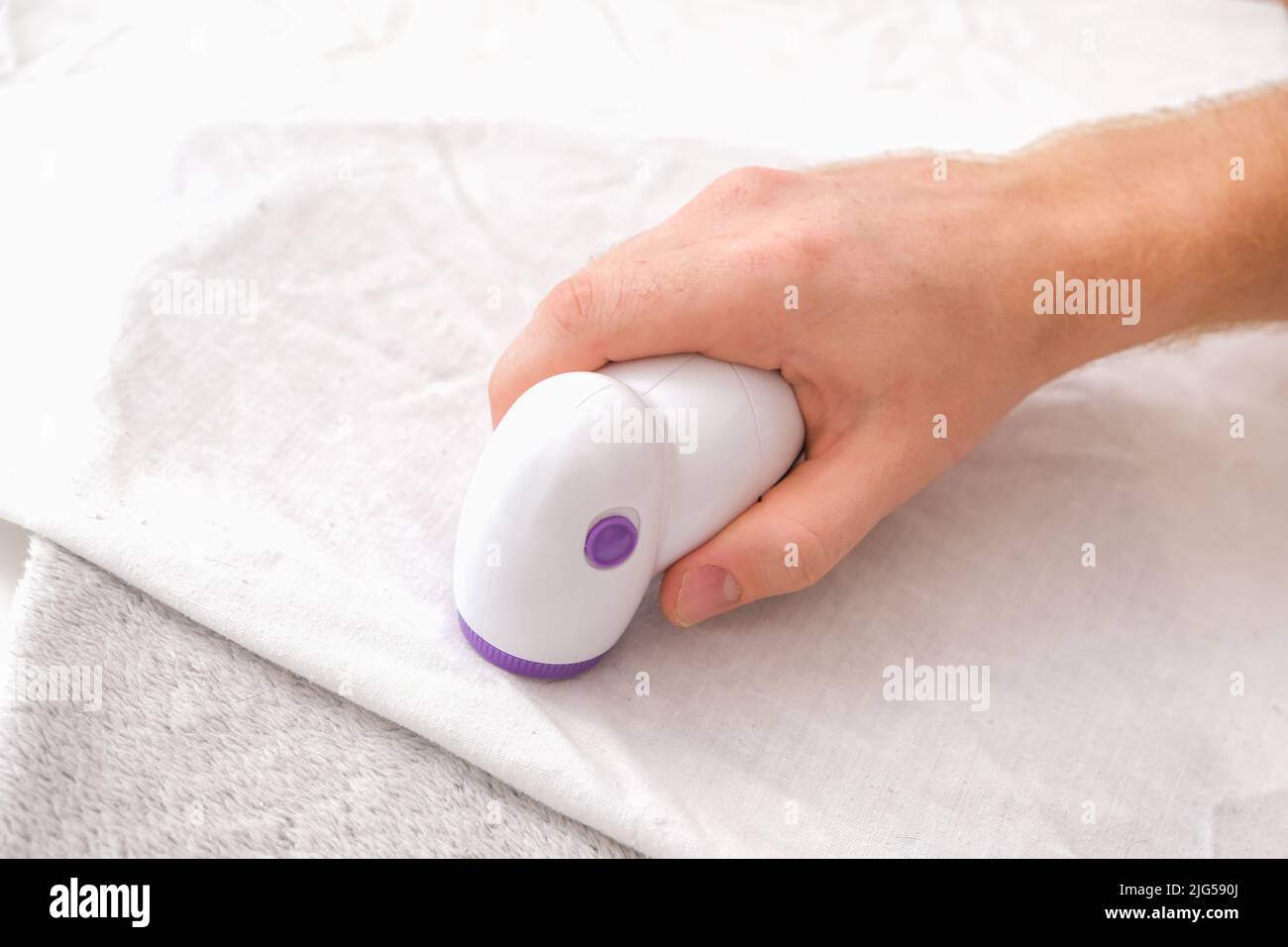 Der Mann entfernt Stofftabletten mit Flusensieb. Stockfoto