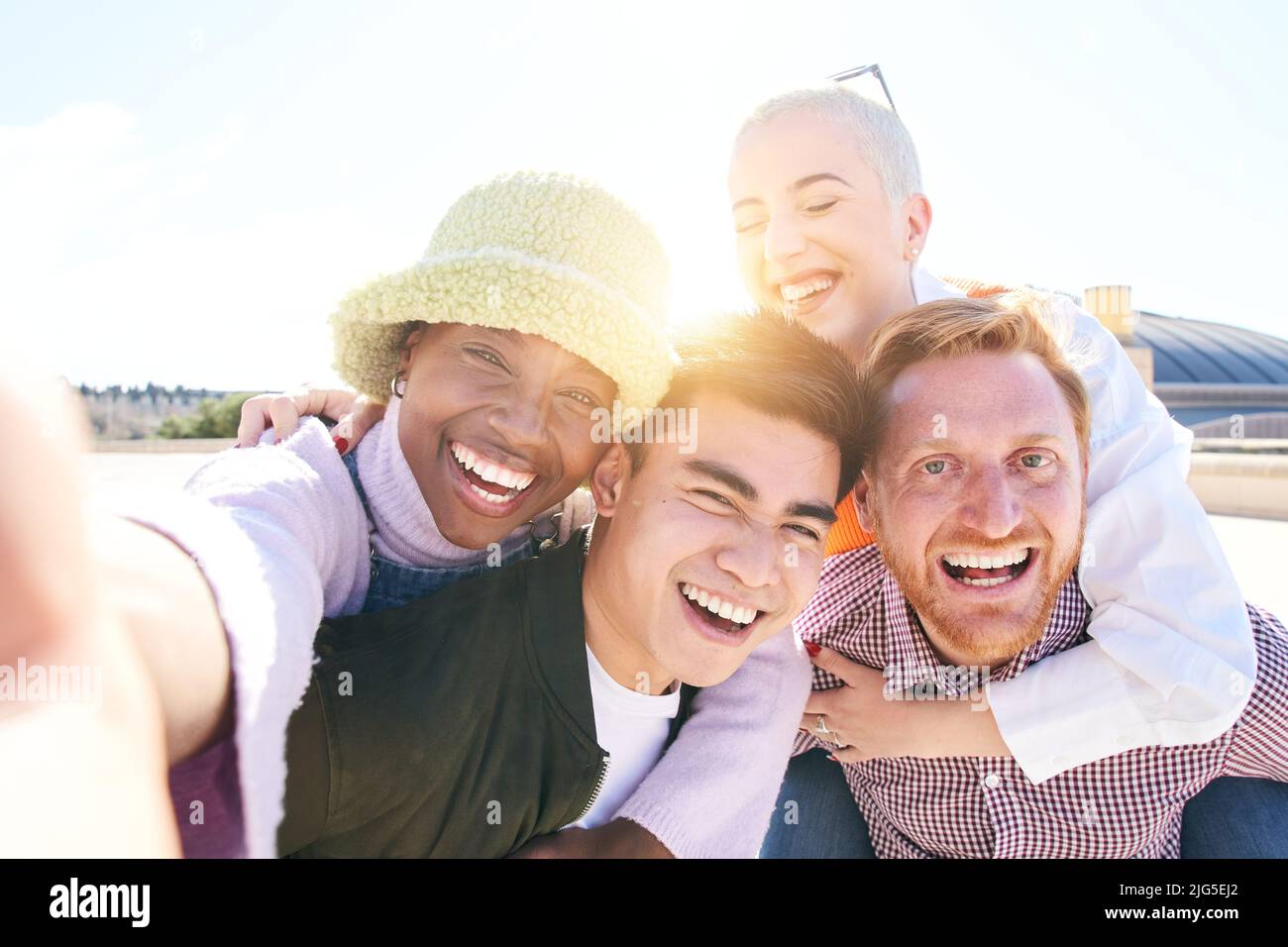 Huckepack-Freunde nehmen an einem sonnigen Tag zusammen ein lächelndes Selfie im Freien auf. Selbstporträt einer Gruppe junger Menschen, die Spaß miteinander haben. Jungs und Mädchen Stockfoto
