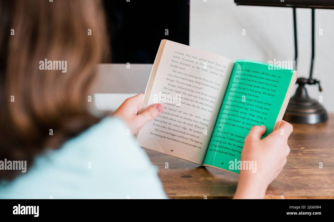 Legasthenie Kind Lesung mit Legasthenie Farbe Overlay in seinem Buch. Eine grüne Farbüberlagerung auf der Seite erleichtert das Lesen. Stockfoto