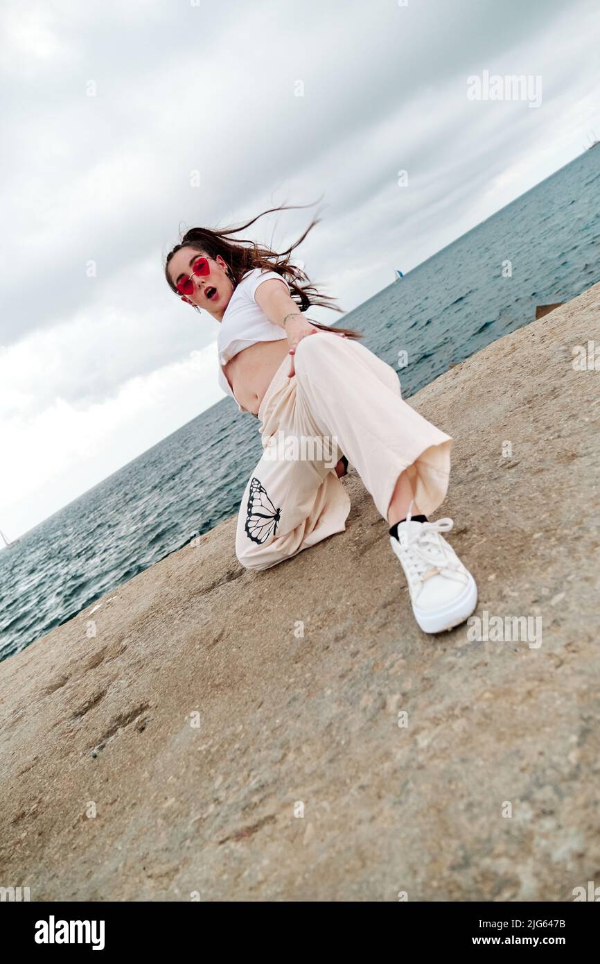 Junge Tänzerin im urbanen Stil, die einen Tanz tanzt, posiert im Freien gegen das Meer. Stockfoto
