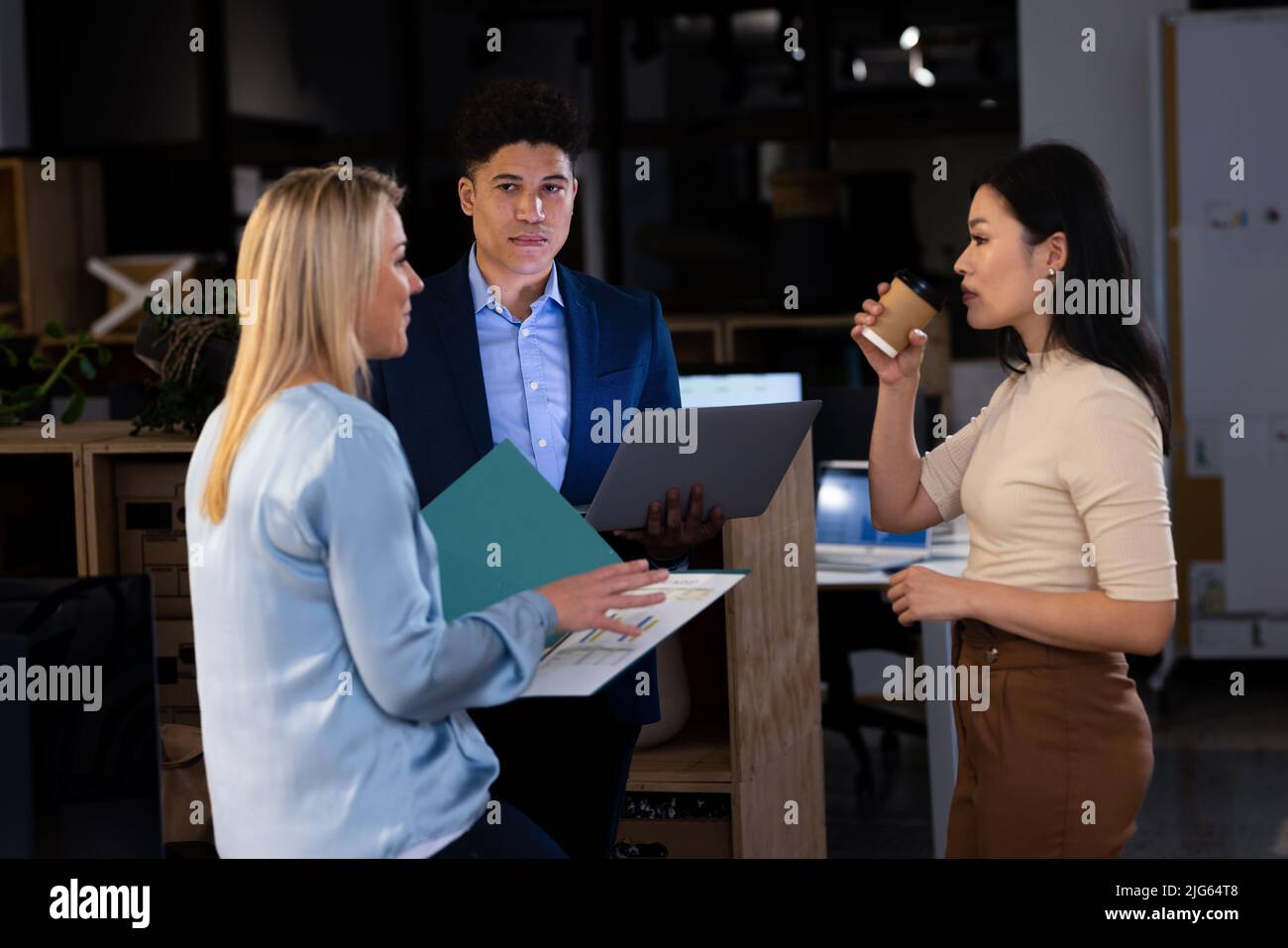 Multirassische Geschäftsfrau mit Bericht, in dem sie Kollegen während ihrer späten Amtszeit über Daten informiert Stockfoto