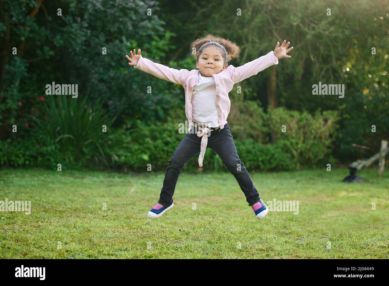 Shes nur ein Ausbruch von Energie. Portrait eines entzückenden kleinen Mädchens, das im Freien springt. Stockfoto