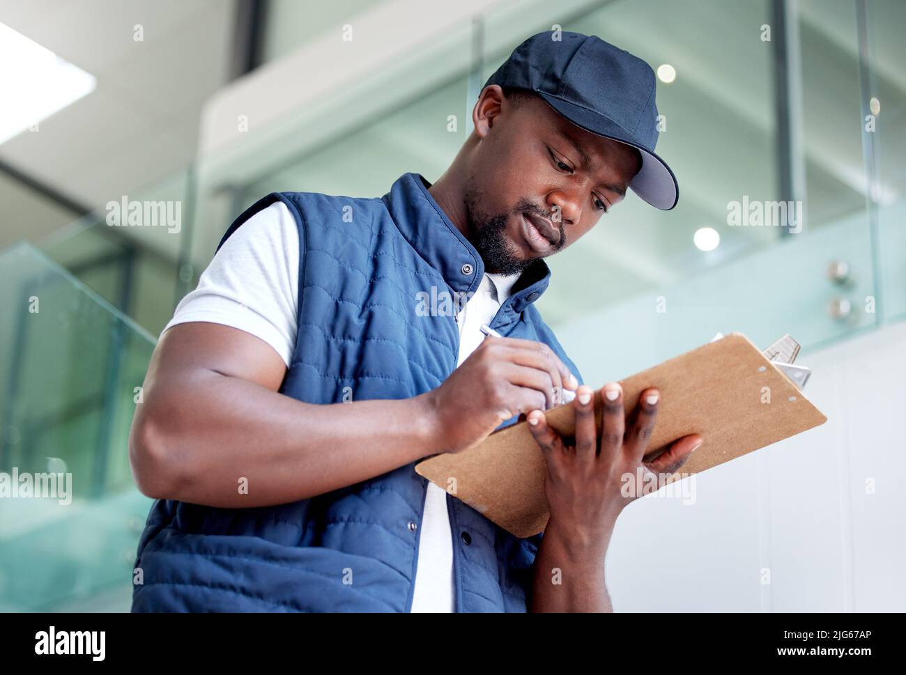 Wir sind bestrebt, pünktlich zu liefern. Aufnahme eines Mannes, der ein Paket in einem Gebäude ausliefert. Stockfoto