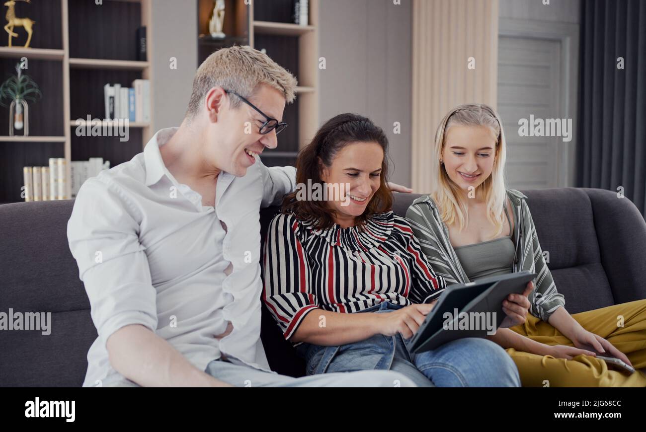 Glückliche kaukasische Familie mit Tablet, Laptop, Telefon zum Spielen von Spielfilmen, Entspannen zu Hause für Technologie Lifestyle-Konzept Stockfoto