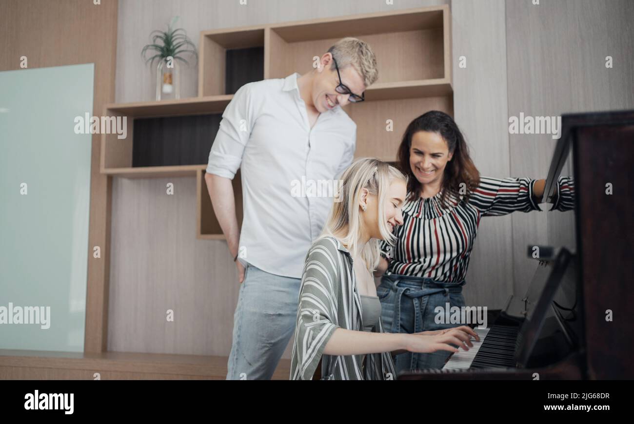Glückliche Familie, Mutter, Vater und Tochter spielen zu Hause Klavier, Konzept für Familienbeziehung. Stockfoto