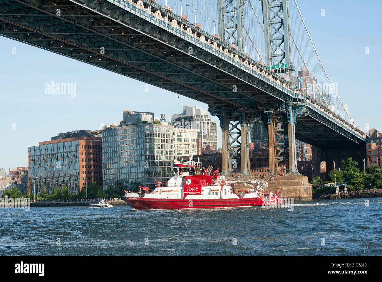 Das Feuerwehrboot der FDNY, Firefighter II, passiert unter der Manhattan Bridge, die den East River überspannt. Firevigher II wurde im Dezember 2010 in Dienst gestellt. I Stockfoto