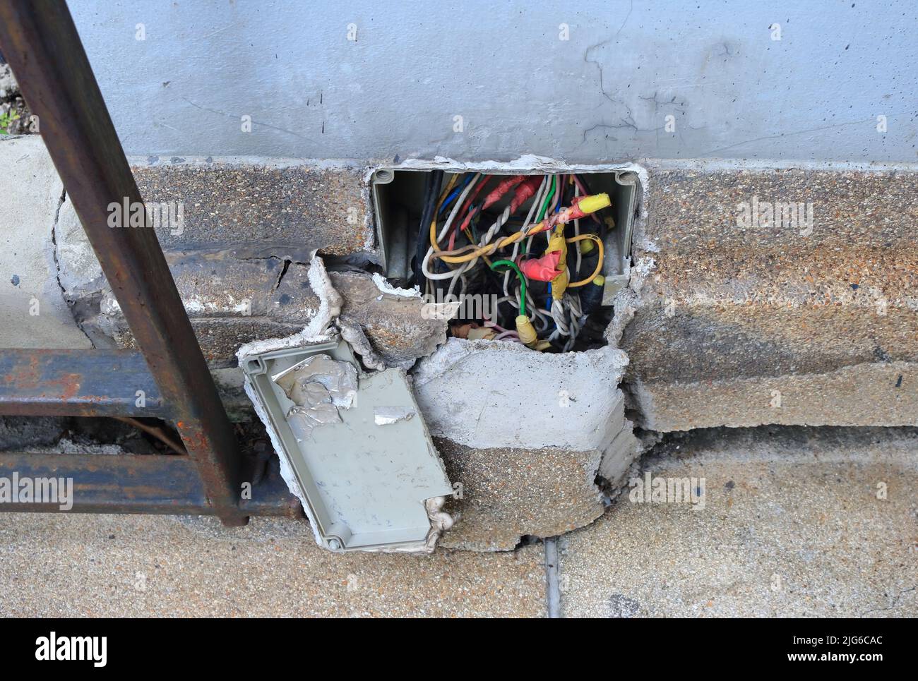 Freiliegende elektrische Kabel in der Anschlussdose in der rissigen Wand, Weitwinkelansicht Stockfoto