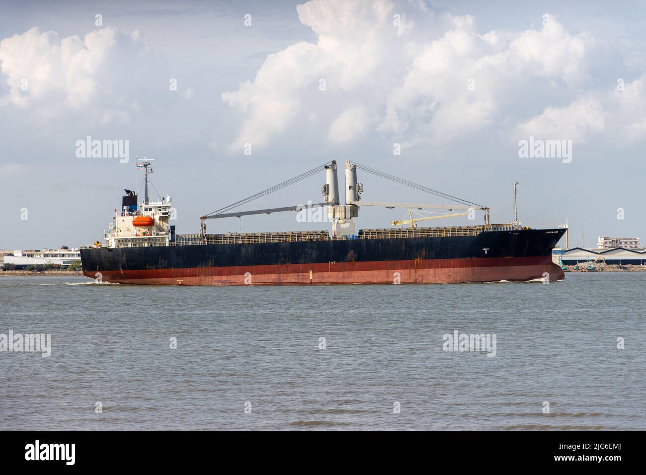 Das Frachtschiff fährt an einem industriellen Ufer entlang Stockfoto