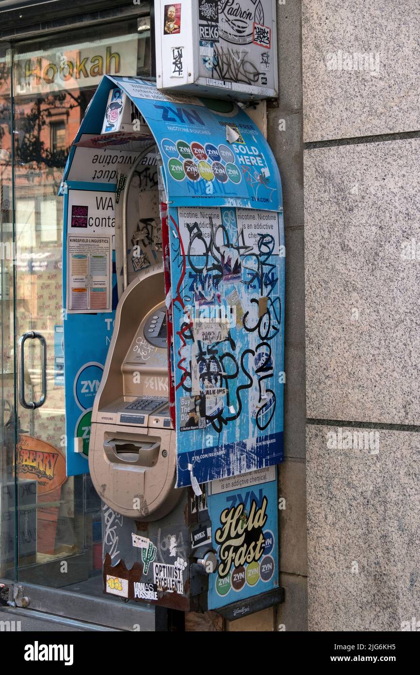 Ein Geldautomat auf der Second Avenue im East Village mit Aufklebern, Graffiti, Schildern und Hinweisen. In Manhattan, New York City. Stockfoto