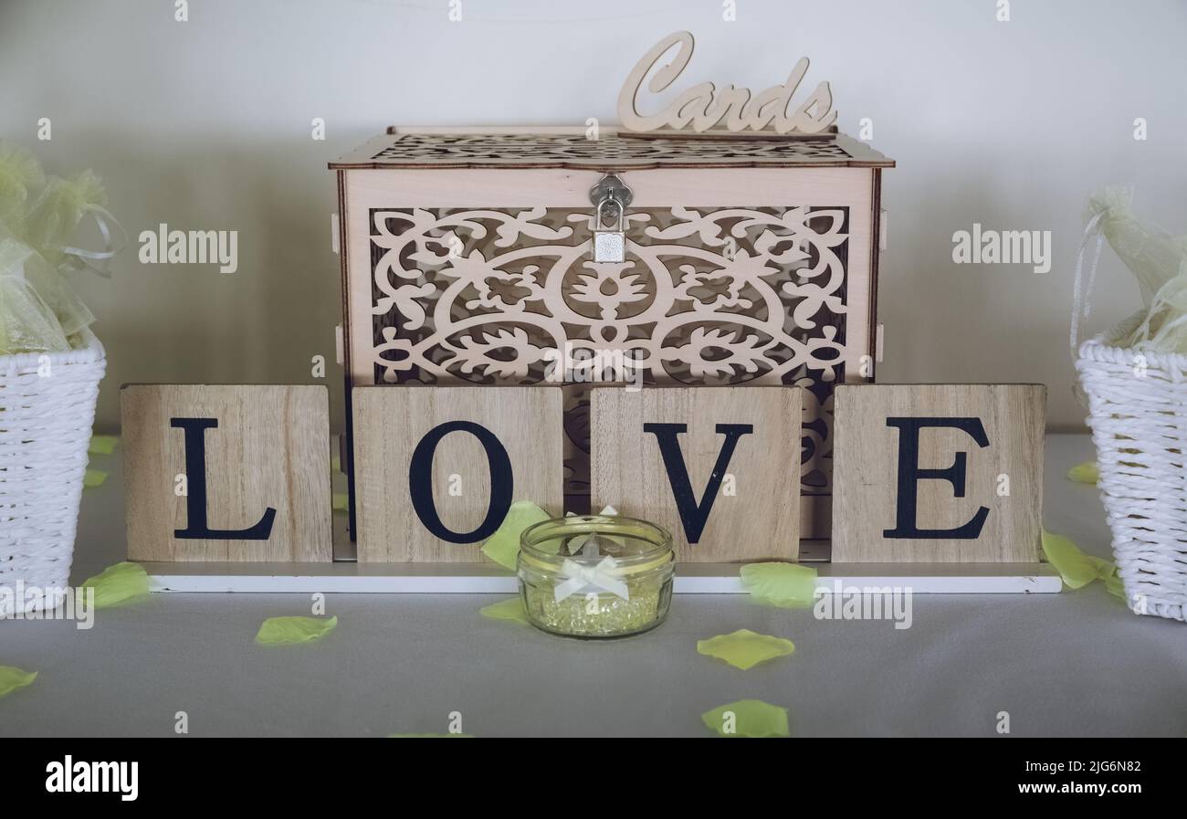 Ein Schild mit der Aufschrift „Liebe“ auf einem Tisch bei einem Hochzeitsempfang vor einer Hochzeitskartekassedose Stockfoto