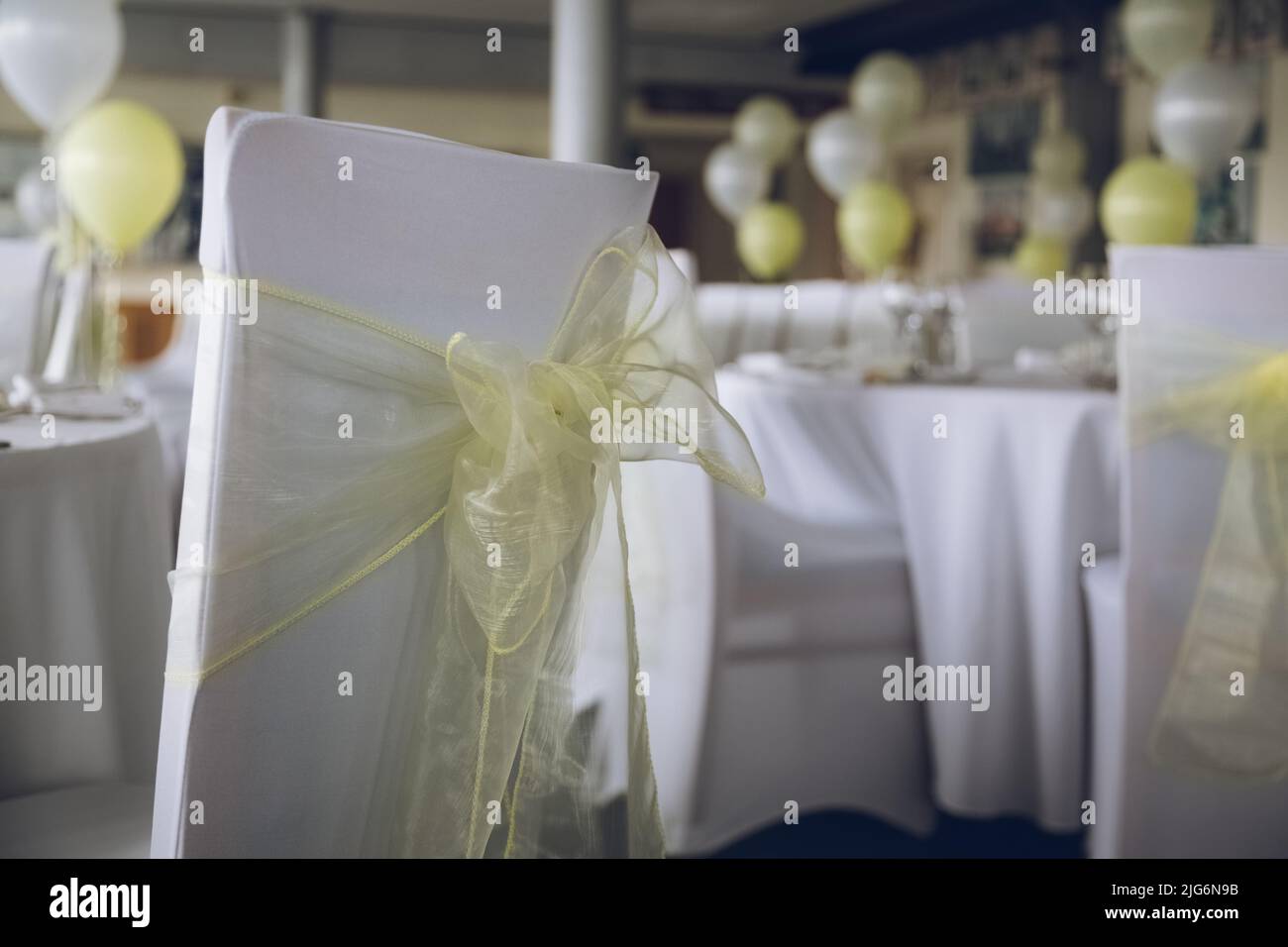 Eine gelbe Schleife auf der Rückseite eines Stuhls bei einem Hochzeitsfrühstück mit selektivem Fokus Stockfoto