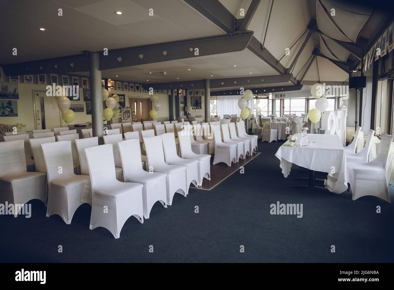 Ein Hochzeitsort, der vor der Ankunft der Gäste mit weißen Stühlen und gelben Dekorationen eingerichtet wird Stockfoto