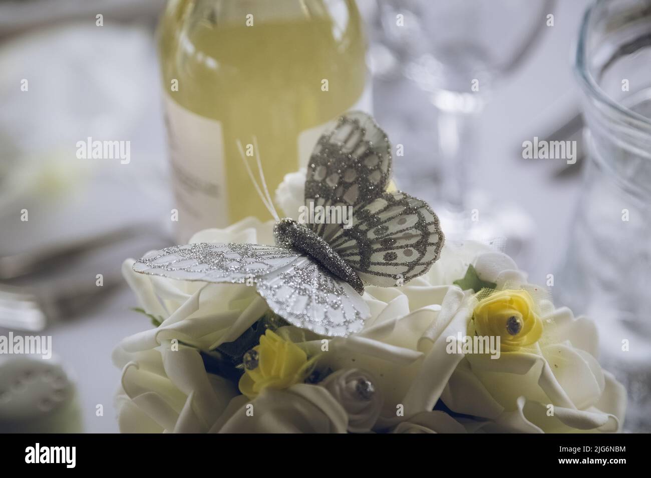 Eine Nahaufnahme eines Schmetterlings der Hochzeitstisch-Dekoration, umgeben von anderen gelben Dekorationen Stockfoto