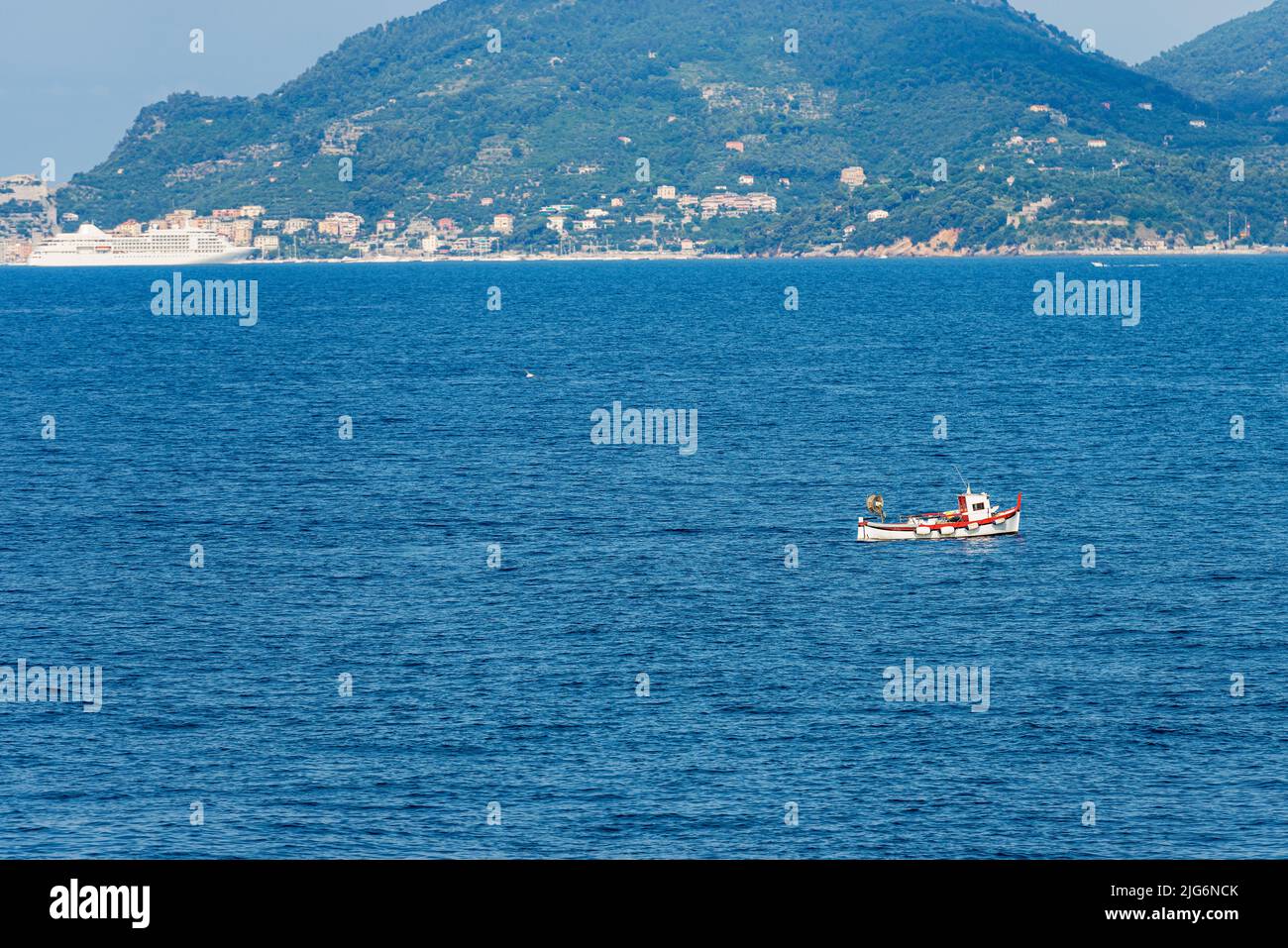 Kleines weißes und rotes Fischerboot im Golf von La Spezia, Mittelmeer, Ligurien, Italien, Europa. Auf dem Hintergrund Porto Venere oder Portovenere Stadt. Stockfoto