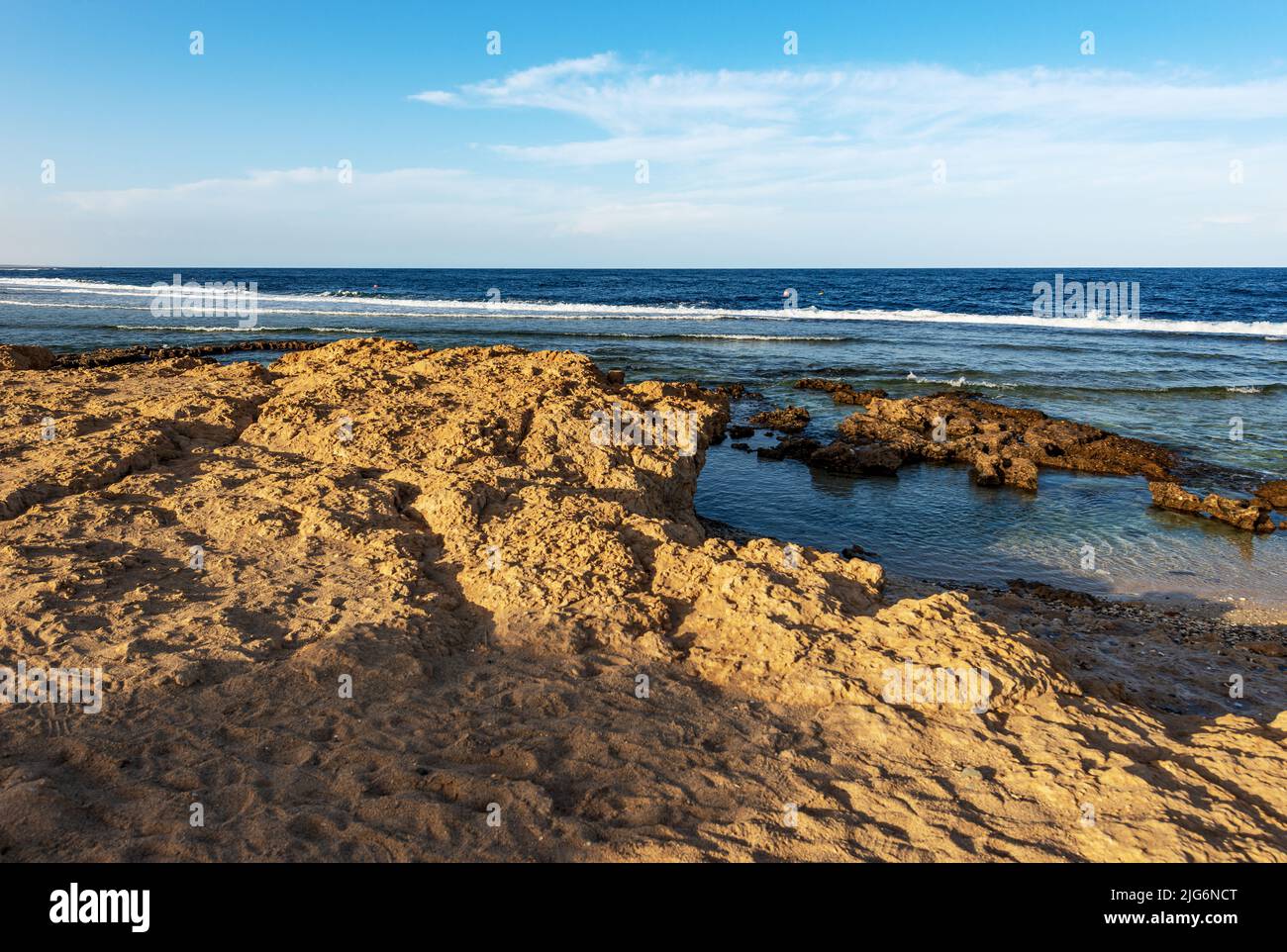Seascape und schöner Fels- und Sandstrand an der Küste des Roten Meeres mit Wellen brechen auf dem Korallenriff, in der Nähe von Marsa Alam, Ägypten, Nordafrika. Stockfoto
