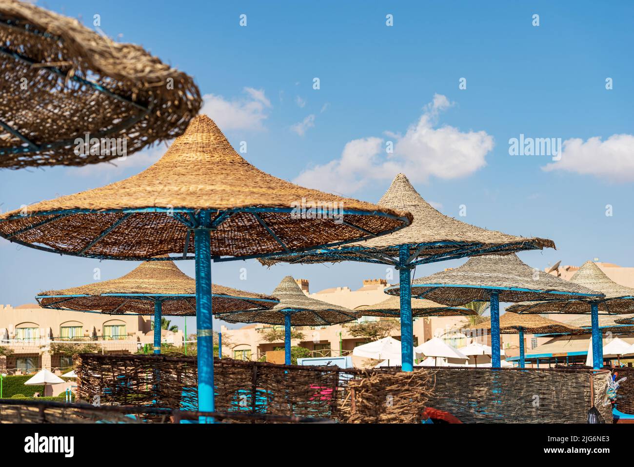 Gruppe von Strohschirmen am Strand. Strandurlaub an der Küste des Roten Meeres in der Nähe von Marsa Alam, Sahara Wüste, Ägypten, Nordafrika. Stockfoto