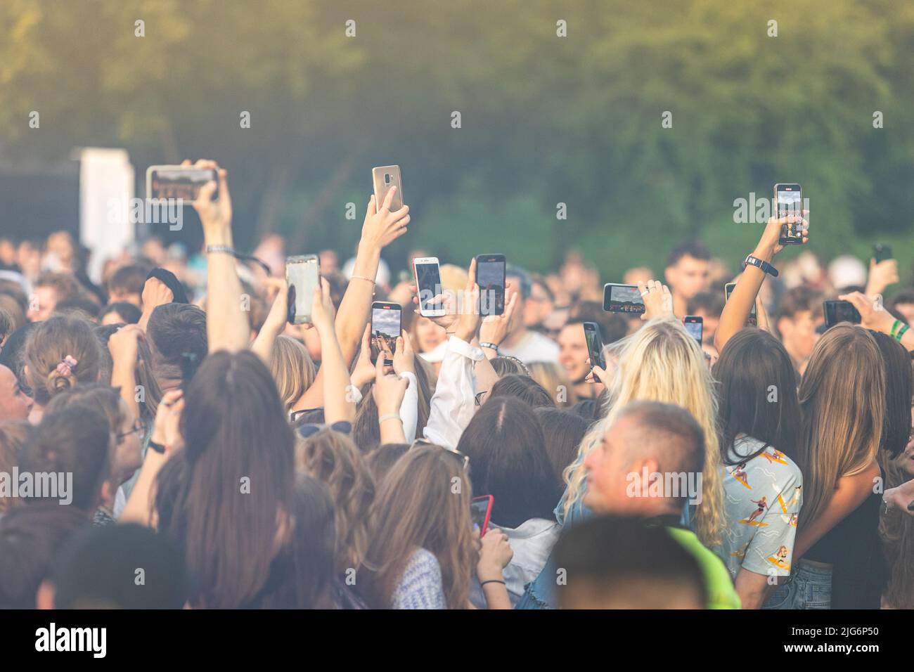 Junge Menschen hoben beim Musikfestival die Hände in die Luft. Menschen, die mit ihren Mobiltelefonen Filmen Stockfoto
